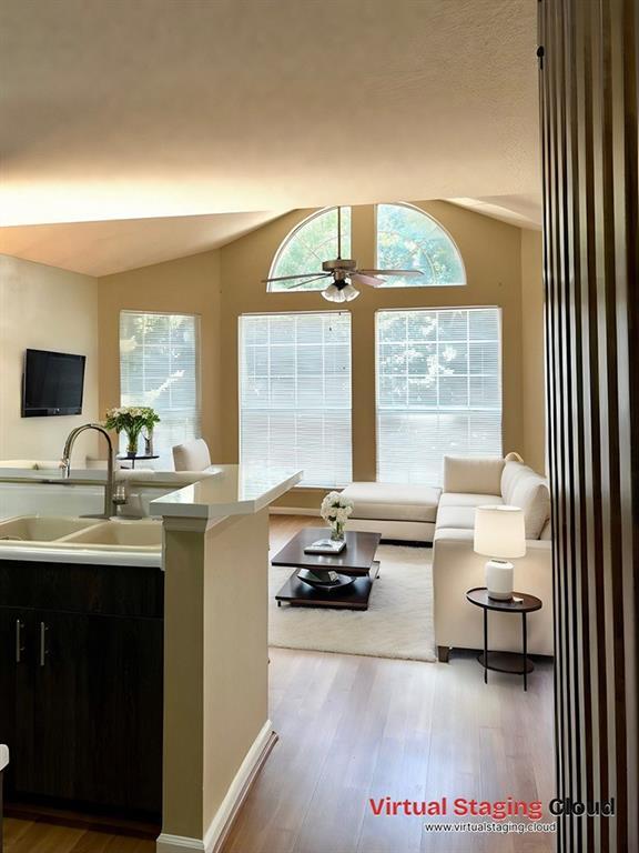 living room featuring hardwood / wood-style floors, vaulted ceiling, ceiling fan, and sink