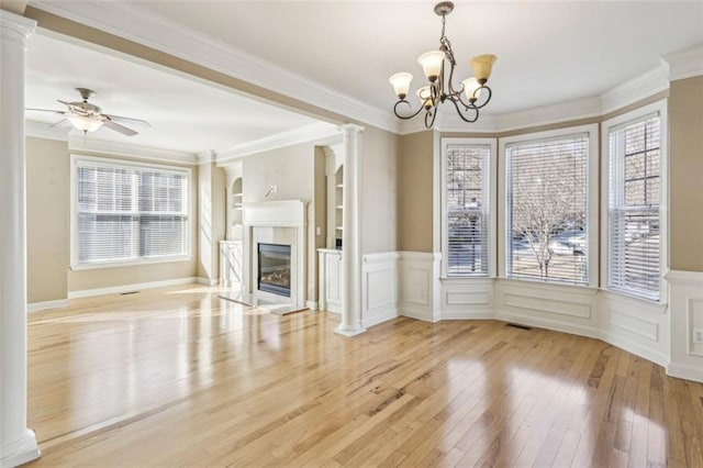 unfurnished living room with built in shelves, ceiling fan with notable chandelier, light hardwood / wood-style flooring, and crown molding