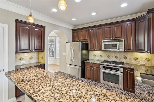 kitchen with hanging light fixtures, backsplash, dark stone countertops, crown molding, and appliances with stainless steel finishes