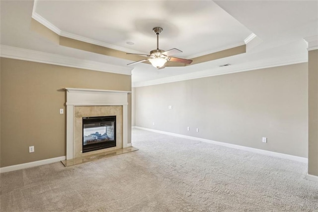 unfurnished living room with a fireplace, a tray ceiling, crown molding, and light colored carpet