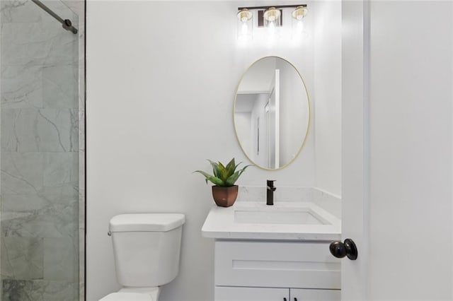 bathroom with a tile shower, vanity, and toilet