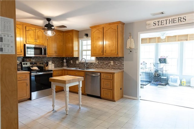 1043 Foxhollow Trl, Canton, GA 30115 - kitchen featuring appliances with stainless steel finishes, ceiling fan, tasteful backsplash, a sink, and light countertops