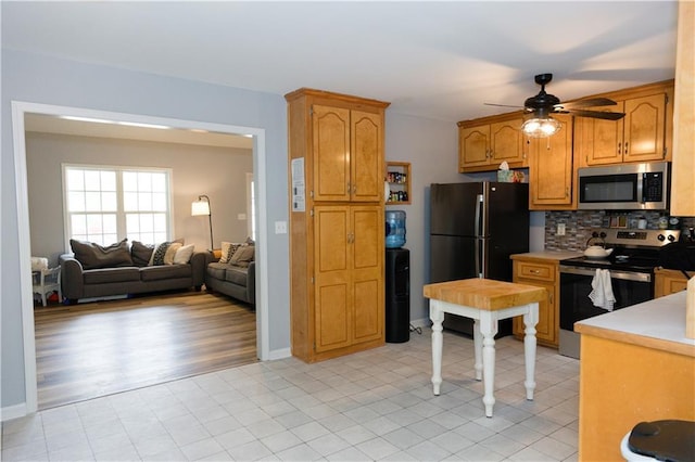 1043 Foxhollow Trl, Canton, GA 30115 - kitchen with appliances with stainless steel finishes, light countertops, ceiling fan, decorative backsplash, and open floor plan