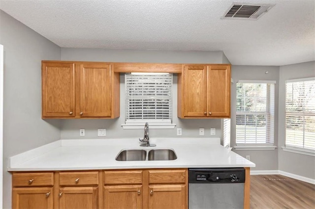 kitchen with light hardwood / wood-style floors, a textured ceiling, sink, and stainless steel dishwasher