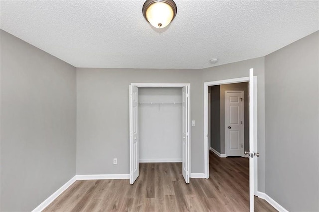 unfurnished bedroom with light wood-type flooring, a closet, and a textured ceiling