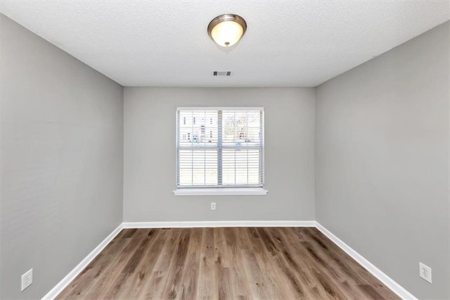 spare room featuring a textured ceiling and hardwood / wood-style floors