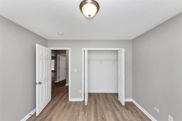 unfurnished bedroom with light wood-type flooring, a closet, and a textured ceiling