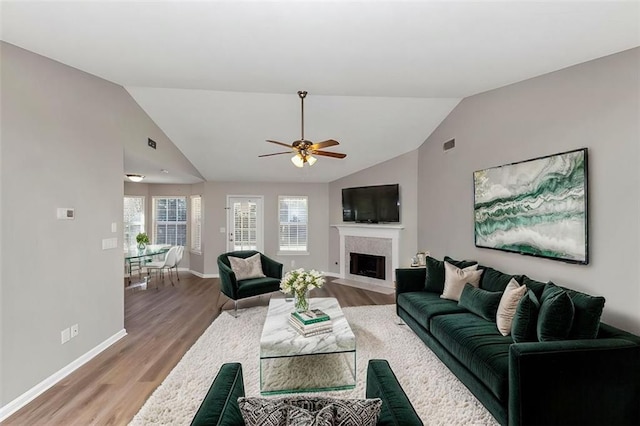 living room featuring ceiling fan, vaulted ceiling, wood-type flooring, and a high end fireplace