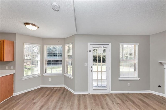 doorway with light hardwood / wood-style floors and a textured ceiling