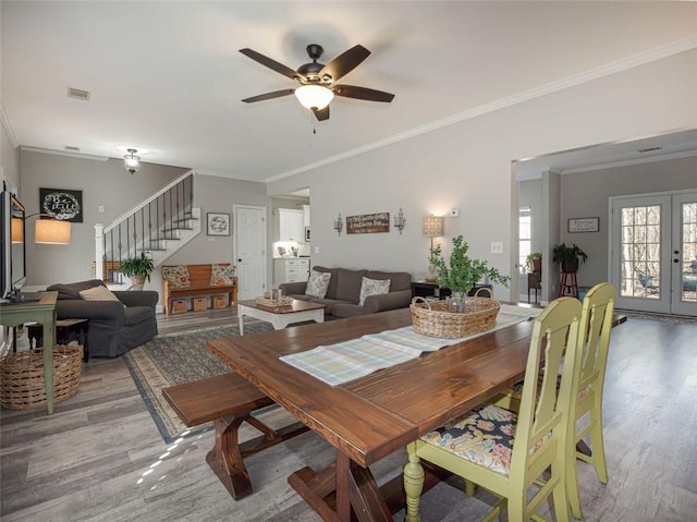 dining area featuring visible vents, a ceiling fan, wood finished floors, french doors, and stairs