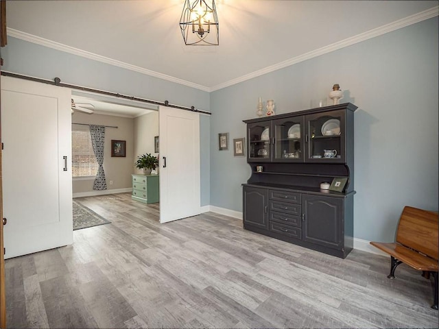 interior space featuring a barn door, light wood-style floors, and crown molding