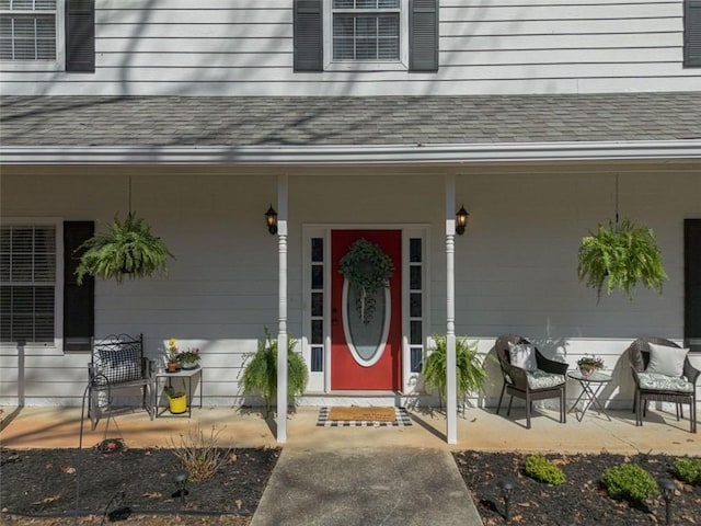 entrance to property with covered porch and roof with shingles