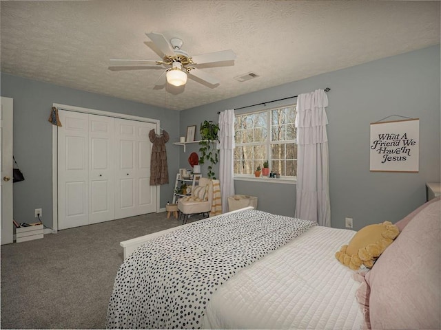 carpeted bedroom featuring a closet, visible vents, a textured ceiling, and a ceiling fan