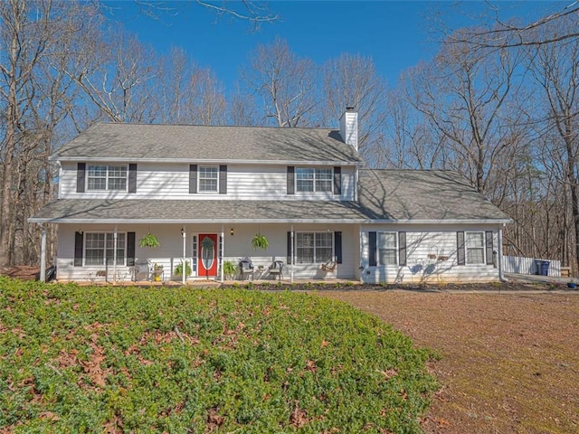 view of front facade with a front yard, a porch, and a chimney