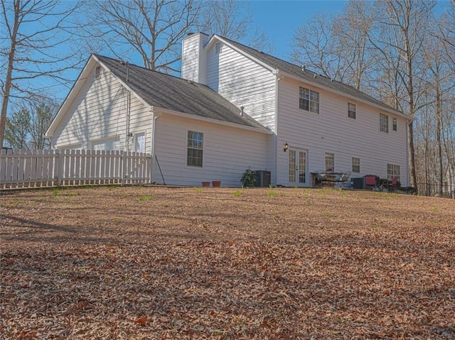 back of house featuring central air condition unit, french doors, a chimney, and fence