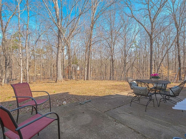 view of patio / terrace featuring outdoor dining area and a wooded view