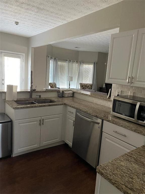 kitchen featuring sink, dark hardwood / wood-style floors, a textured ceiling, white cabinetry, and stainless steel appliances