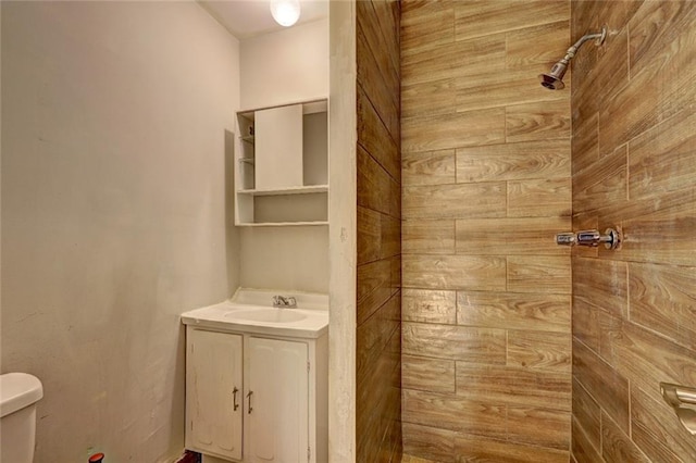 bathroom featuring vanity, toilet, and tiled shower