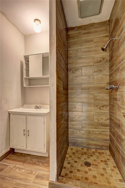 bathroom with vanity, wood-type flooring, and tiled shower