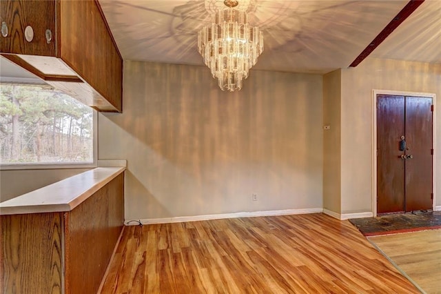 unfurnished dining area with a chandelier and light hardwood / wood-style floors