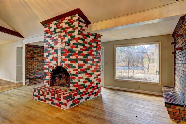 unfurnished living room with a brick fireplace, beamed ceiling, and hardwood / wood-style flooring