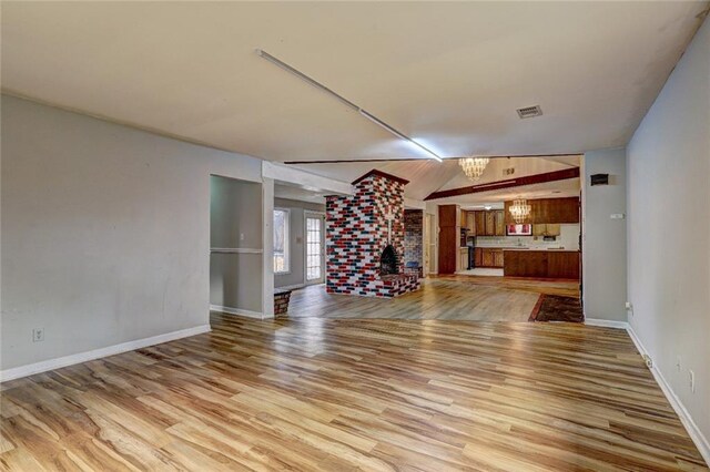 unfurnished living room featuring a notable chandelier, light hardwood / wood-style floors, and lofted ceiling