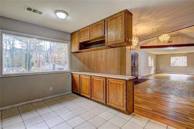 kitchen with lofted ceiling, hanging light fixtures, a notable chandelier, light hardwood / wood-style floors, and kitchen peninsula