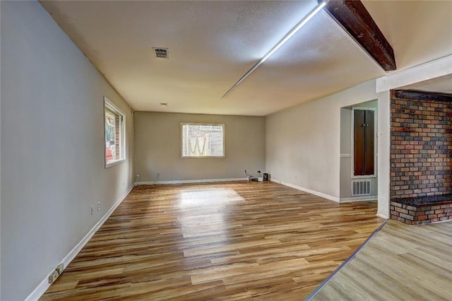 spare room featuring beamed ceiling and light wood-type flooring