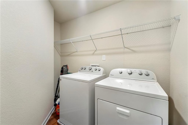 clothes washing area with hardwood / wood-style flooring and washing machine and dryer