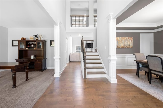 foyer entrance with crown molding, wood-type flooring, and ornate columns