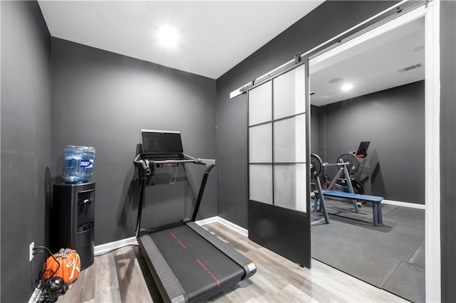 workout area featuring hardwood / wood-style flooring and a barn door