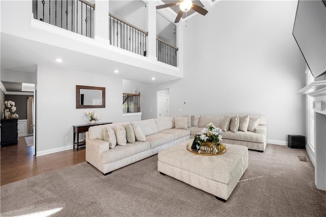 living room with a high ceiling, hardwood / wood-style flooring, and ceiling fan