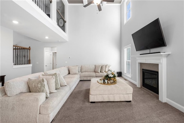 living room featuring a high ceiling, ceiling fan, and carpet