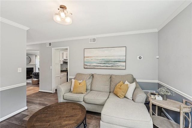 living room featuring wood finished floors, crown molding, baseboards, and a fireplace