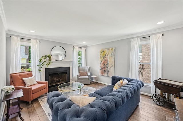 living room featuring a tile fireplace, crown molding, wood-type flooring, recessed lighting, and baseboards