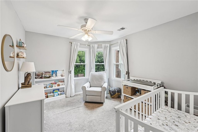 bedroom with a crib, carpet, and a ceiling fan