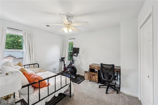 bedroom with multiple windows, carpet, a closet, and ceiling fan