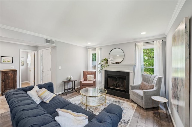 living area featuring a fireplace, wood finished floors, recessed lighting, crown molding, and baseboards