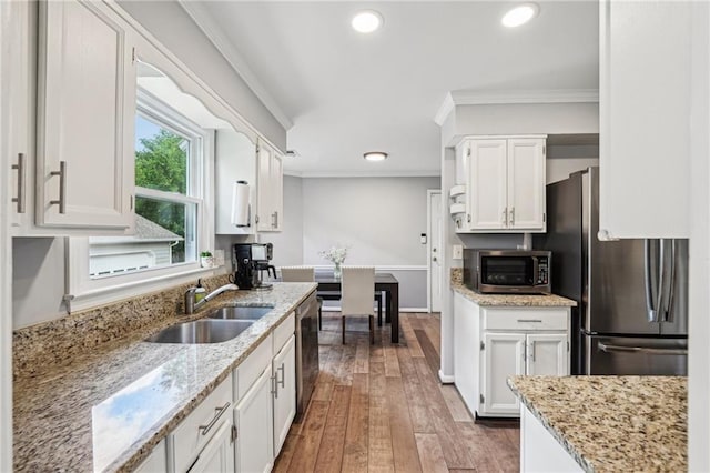 kitchen with stainless steel appliances, a sink, ornamental molding, white cabinetry, and hardwood / wood-style flooring
