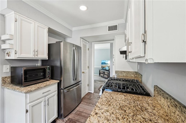 kitchen featuring gas stove, crown molding, white cabinetry, freestanding refrigerator, and wood finished floors