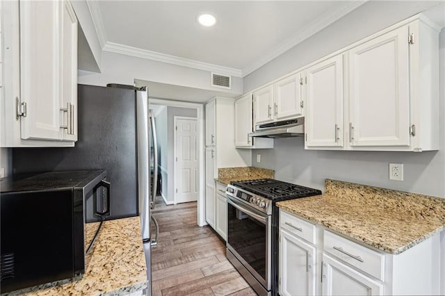 kitchen featuring stainless steel gas stove, under cabinet range hood, black microwave, light wood-style flooring, and ornamental molding