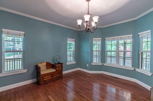 unfurnished room featuring ornamental molding, a notable chandelier, dark hardwood / wood-style flooring, and a healthy amount of sunlight