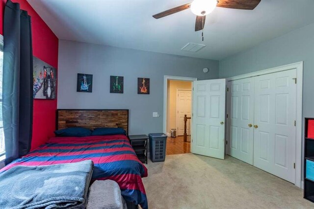 bedroom with a closet, ceiling fan, and light colored carpet