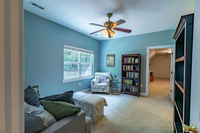 living area featuring light carpet and ceiling fan