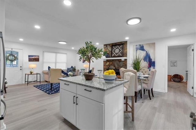 kitchen with light wood finished floors, white cabinetry, open floor plan, light stone counters, and recessed lighting