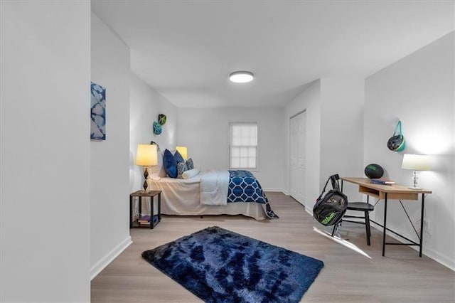 bedroom with baseboards, wood finished floors, and a closet