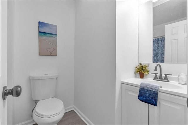 full bath with toilet, baseboards, vanity, and wood finished floors