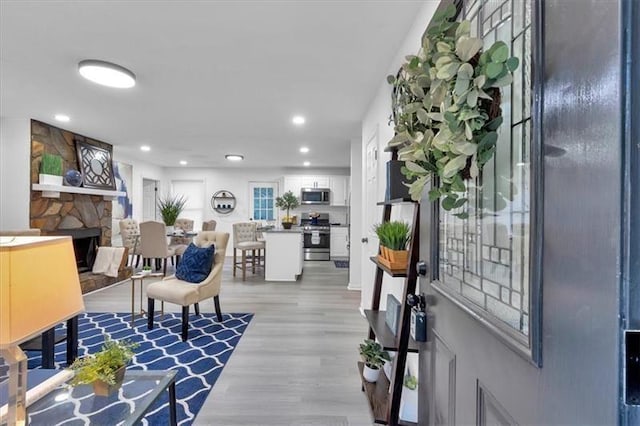 living room featuring recessed lighting, a stone fireplace, and light wood finished floors