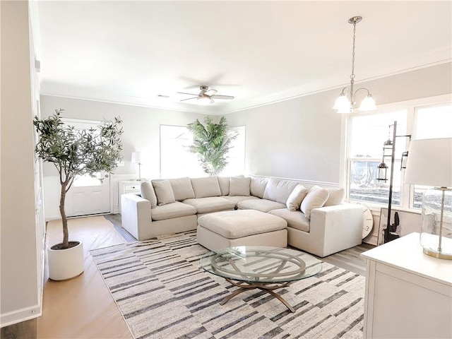 living room with ceiling fan with notable chandelier, crown molding, and light hardwood / wood-style flooring