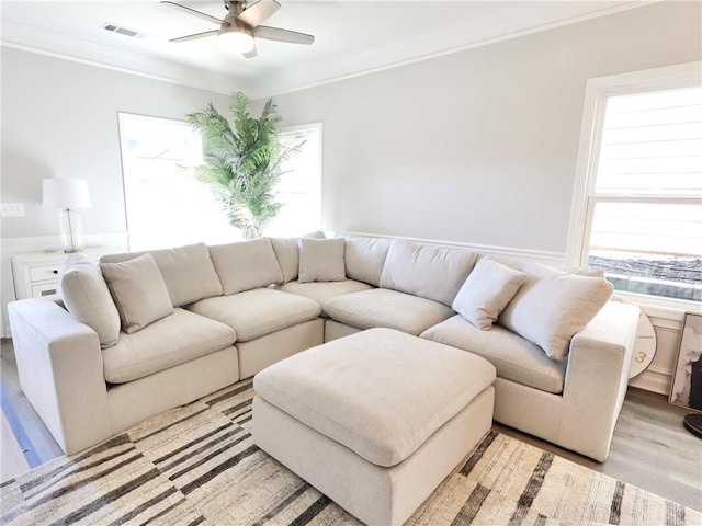 living room with ceiling fan, light wood-type flooring, and crown molding